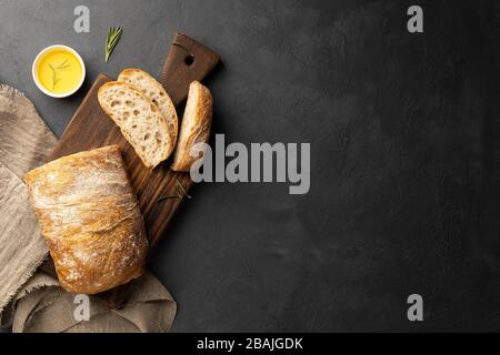 Sliced Italian ciabatta bread on black background. Top view, flat lay. Copy space for text. Stock Photo