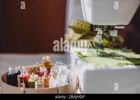 White sewing machine and colorful threads with needles and measuring tape Stock Photo