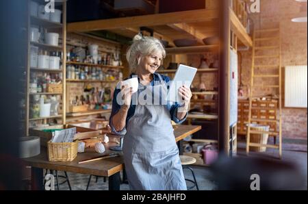 Portrait of senior female pottery artist in her art studio Stock Photo