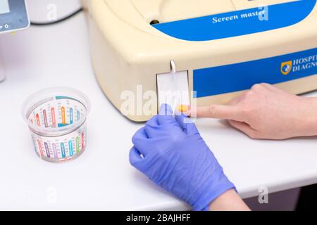Laboratory assistant in medical laboratory holds test tube with blood and plasma in his hand and doing analysis. Stock Photo