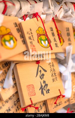 tokyo, japan - march 02 2020: Shinto wooden plaques decorated with a radish and drawstring bag for prosperity in marriage and business in the Shinjoui Stock Photo