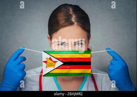 Coronavirus in Zimbabwe Female Doctor Portrait hold protect Face surgical medical mask with Zimbabwe National Flag. Illness, Virus Covid-19 Zimbabwe Stock Photo