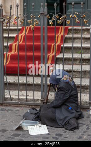 beggar woman on steps of Santi Vincenzo e Anastasio church near Trevi Fountain, Rome Stock Photo