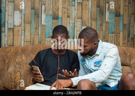 two african student studying their books and felt surprise about what he saw on his phone Stock Photo