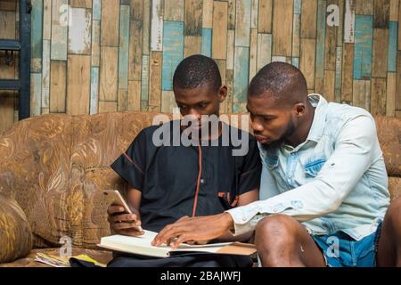 two african student studying their books and holding a smartphone Stock Photo