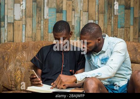 two african student studying their books and holding a smartphone Stock Photo