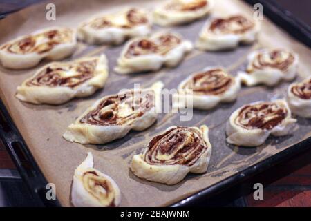 sweet rolls with cinnamon on the tray - backery or cooking at home. A detail of raw cinnamon buns - very shallow depth of field. Stock Photo