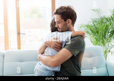 Father embracing son while sitting on sofa at home Stock Photo