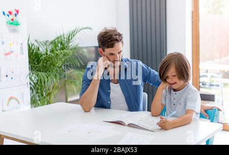 Father and son doing homework together at home Stock Photo