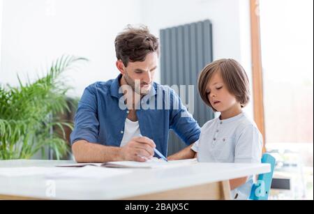 Father and son doing homework together at home Stock Photo