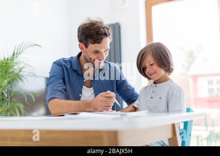 Father and son doing homework together at home Stock Photo
