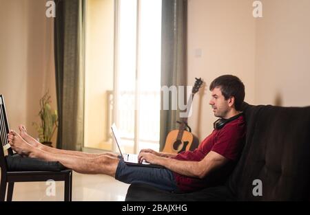 Man working from home while beeing cozy in the livingroom sofa Stock Photo