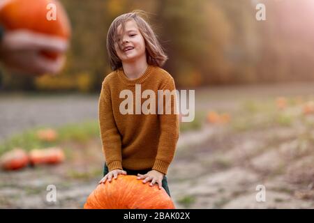 Cute little boy having fun in a pumpkin patch Stock Photo