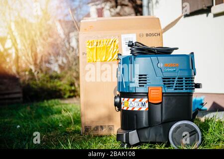Strasbourg, France - Feb 9, 2020: Unboxing new Bosch GAS 35 M AFC Professional Wet Dry Vacuum Cleaner on green grass near reconsutructed home Stock Photo