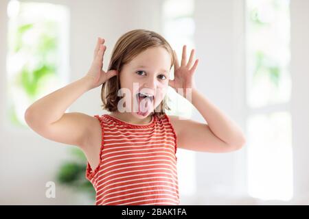 Child making funny face. Kid teasing and laughing. Silly little girl playing and smiling. Stock Photo