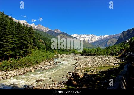 Snow clad himalayas viewed from The Beas River in Manali from Leh - manali highway in summer morning of May, India.Himachal Pradesh Stock Photo