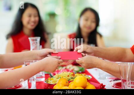 Chinese New Year celebration. Family celebrating winter holiday. Traditional festive dinner in China. Parents, grandparent and kids eating and giving Stock Photo