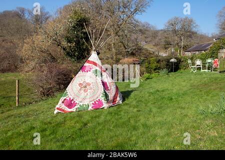 Children's homemade tipi with Indian ethnic embroidery fabric textile exterior in a country garden on a sunny day in spring Wales UK KATHY DEWITT Stock Photo