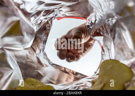 Creative view from inside a bag of potato chips with a hand reaching for a chip Stock Photo