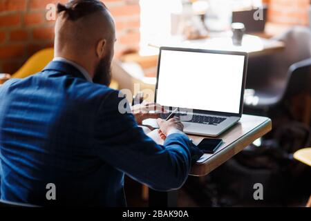 businessman in the office makes notes in a notebook. A student works in a laptop behind a laptop. close-up of computer, hands, and notebook Stock Photo