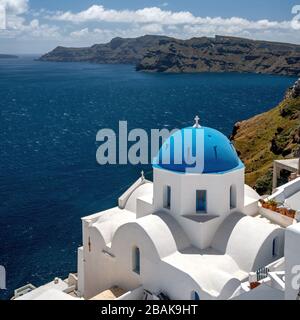 White church with blue dome in Oia Santorini Greece overlooking the Agean sea on a sunny day Stock Photo