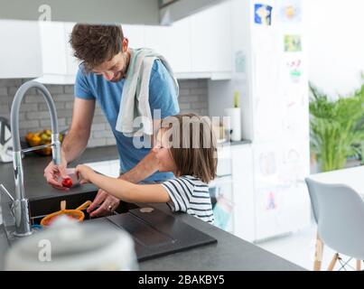 Children helping father in kitchen Stock Photo