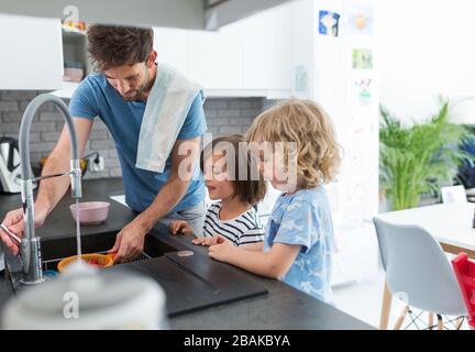 Children helping father in kitchen Stock Photo