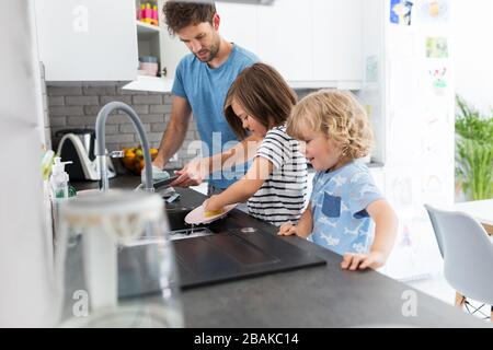 Children helping father in kitchen Stock Photo