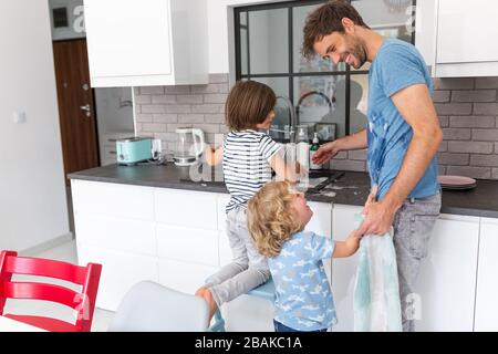 Children helping father in kitchen Stock Photo