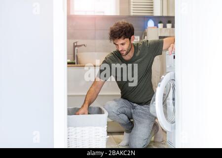 Man Putting his Laundry into a Washing Machine Stock Photo