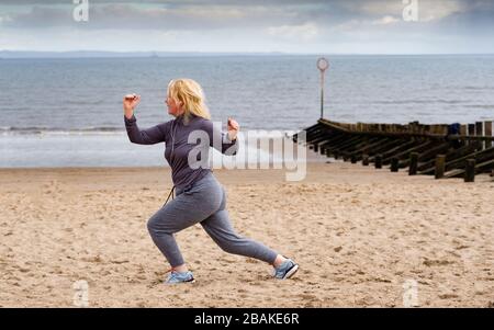 Portobello, Scotland, UK. 28 March, 2020. On the first weekend of the coronavirus lockdown the public were outdoors exercising and maintaining social distancing along Portobello beachfront promenade. Pictured; Annabel Meikle from Portobello working out on her special covid-19  solo training program set by her personal trainer. Iain Masterton/Alamy Live News Stock Photo