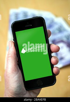 A woman holding a mobile phone showing Leek United Building Society (editorial use only) Stock Photo