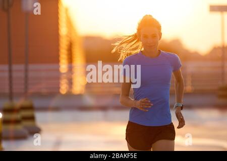 Young woman doing fitness exercise on parking level in the city at sunset Stock Photo