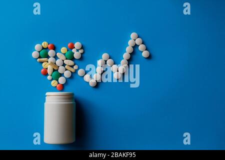 Heap of pills on blue background Assorted pharmaceutical medicine pills, tablets and capsules and bottle on blue background.