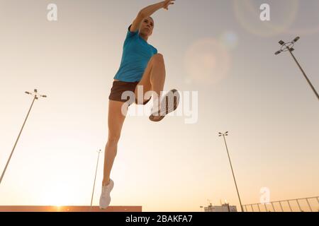 Young woman doing fitness exercise on parking level in the city at sunset Stock Photo