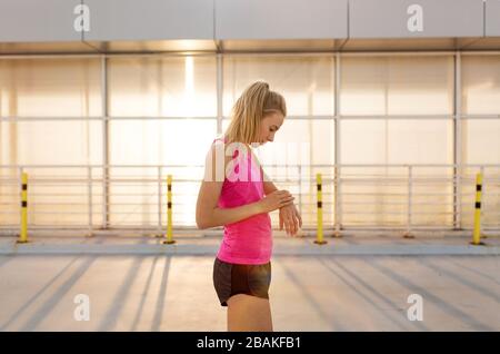 Young woman doing fitness exercise on parking level in the city at sunset Stock Photo