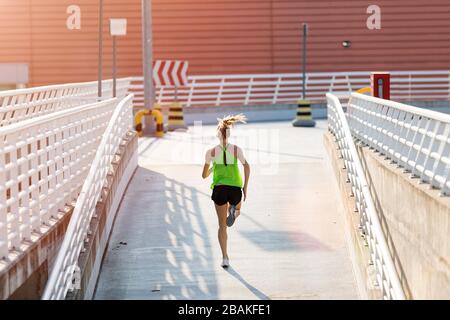 Young woman doing fitness exercise on parking level in the city at sunset