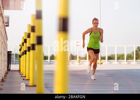 Young woman doing fitness exercise on parking level in the city at sunset