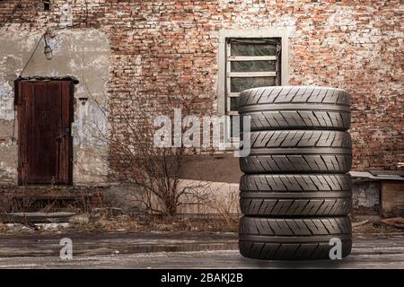 a stack of summer tires against a brick wall. Stock Photo