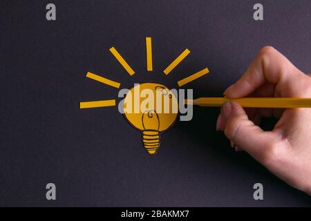 A yellow pencil in hand next to a creative painted light bulb. The concept of innovation and creative ideas Stock Photo