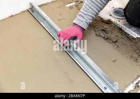 construction worker aligns concrete screed floor Stock Photo