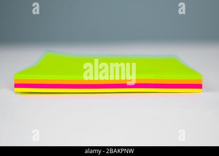 Side view of a stack of different colored paper sticky notes on top of a white desk Stock Photo