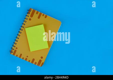 Yellow sticky notes on top of a yellow covered diary before a light blue paper background Stock Photo