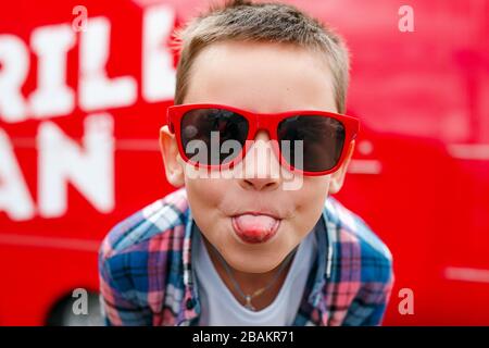 Naughty boy sticks out tongue outdoors in city Stock Photo