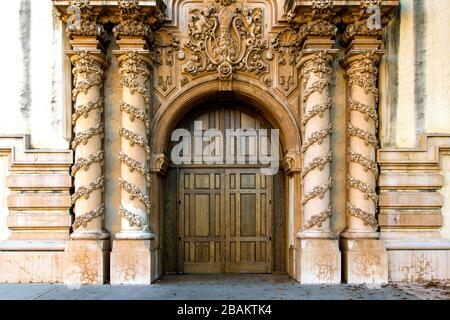 Arched oak wood door in an old building framed by columns with ornate rococo and baroque architectural elements Stock Photo