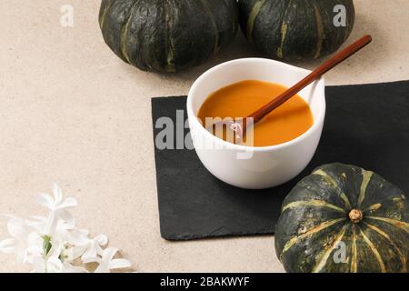Pumpkin soup in a bowl with wooden spoon and minimalist elegant decorations Stock Photo