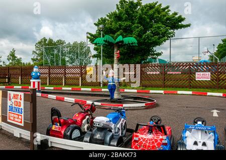 Plastic policemen are located in the centre island of a fun racing circuit for children as small imitation race bikes and cars wait for customers Stock Photo