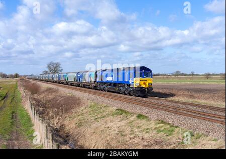 DB cargo maritime livery class 66 locomotive 66047 passing  Mauds Bridge with a freight train train of empty Drax biomass wagons for re loading Stock Photo