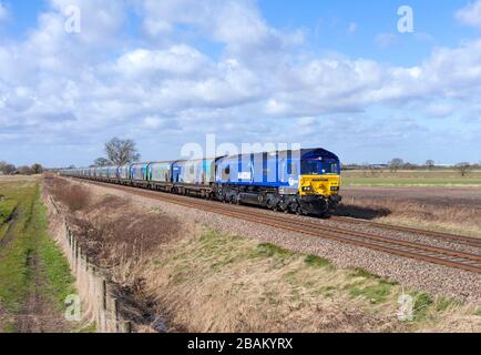 DB cargo maritime livery class 66 locomotive 66047 passing  Mauds Bridge with a freight train train of empty Drax biomass wagons for re loading Stock Photo