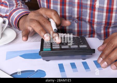 Close up of young man using calculator  Stock Photo